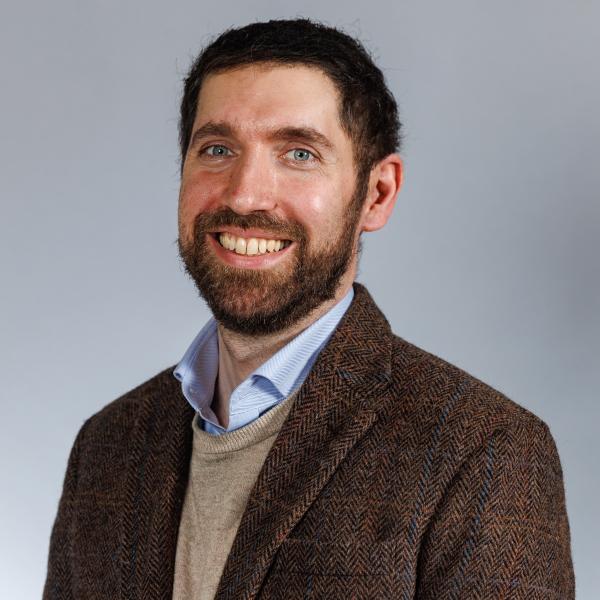 Image of Niall Farrell, man with dark hair, a beard, wearing a blazer