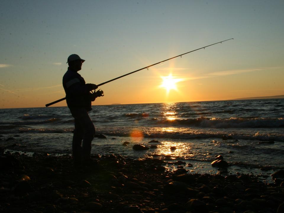 The silhouette of a man is fishing by the seaside