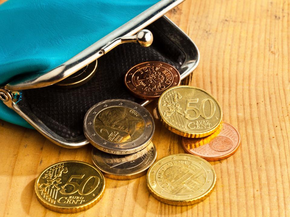 Open purse with coins atop a wooden table