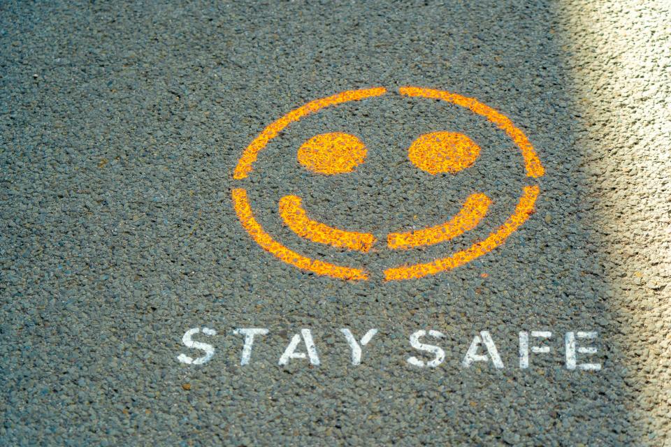 An orange smiley face and the words 'stay save' spray painted on tarmac