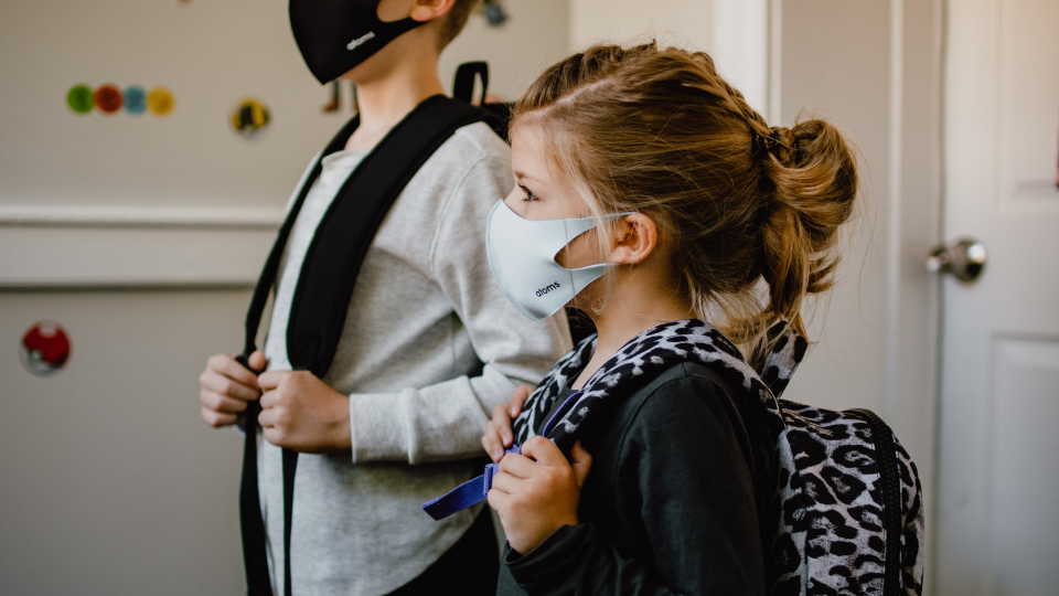 Young girl wearing mask with schoolbag on back