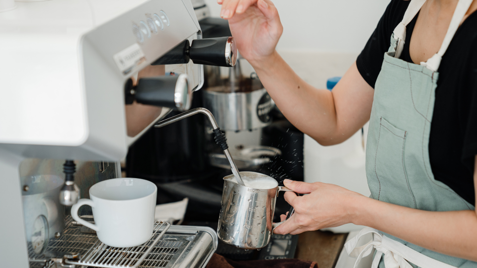 Barista wearing green apron making a coffee