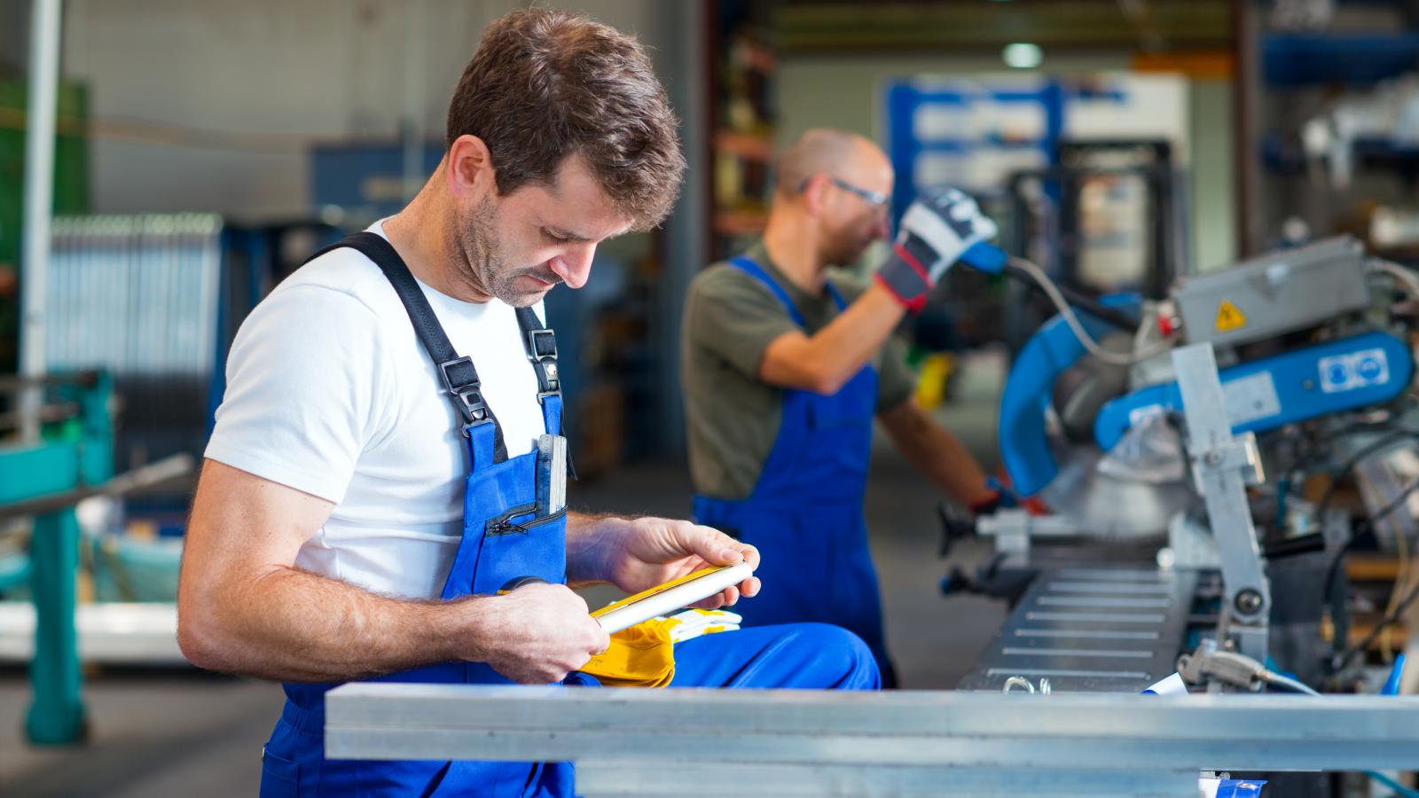 Skilled worker wearing a blue apron is operating a machine in a warehouse