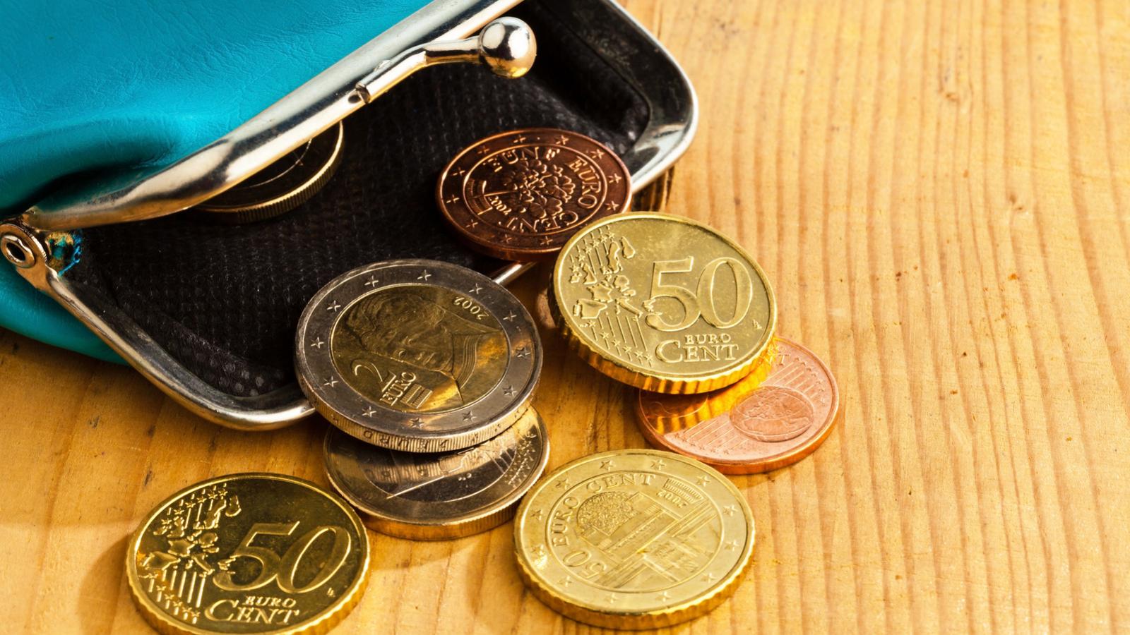 Open purse with coins atop a wooden table