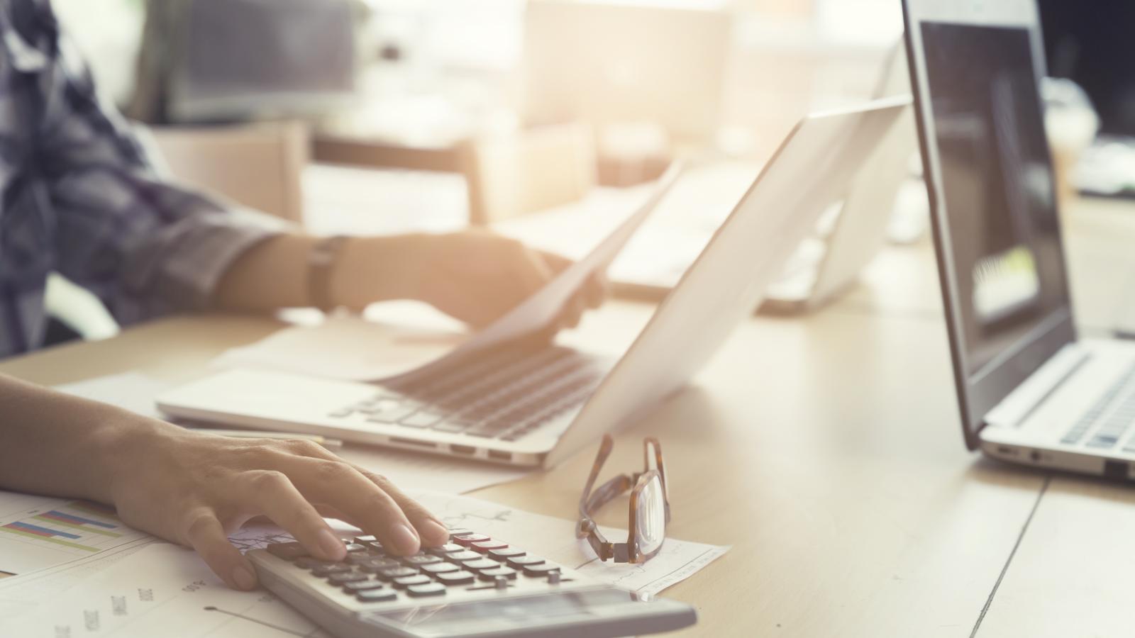 Person using a laptop and a calculator