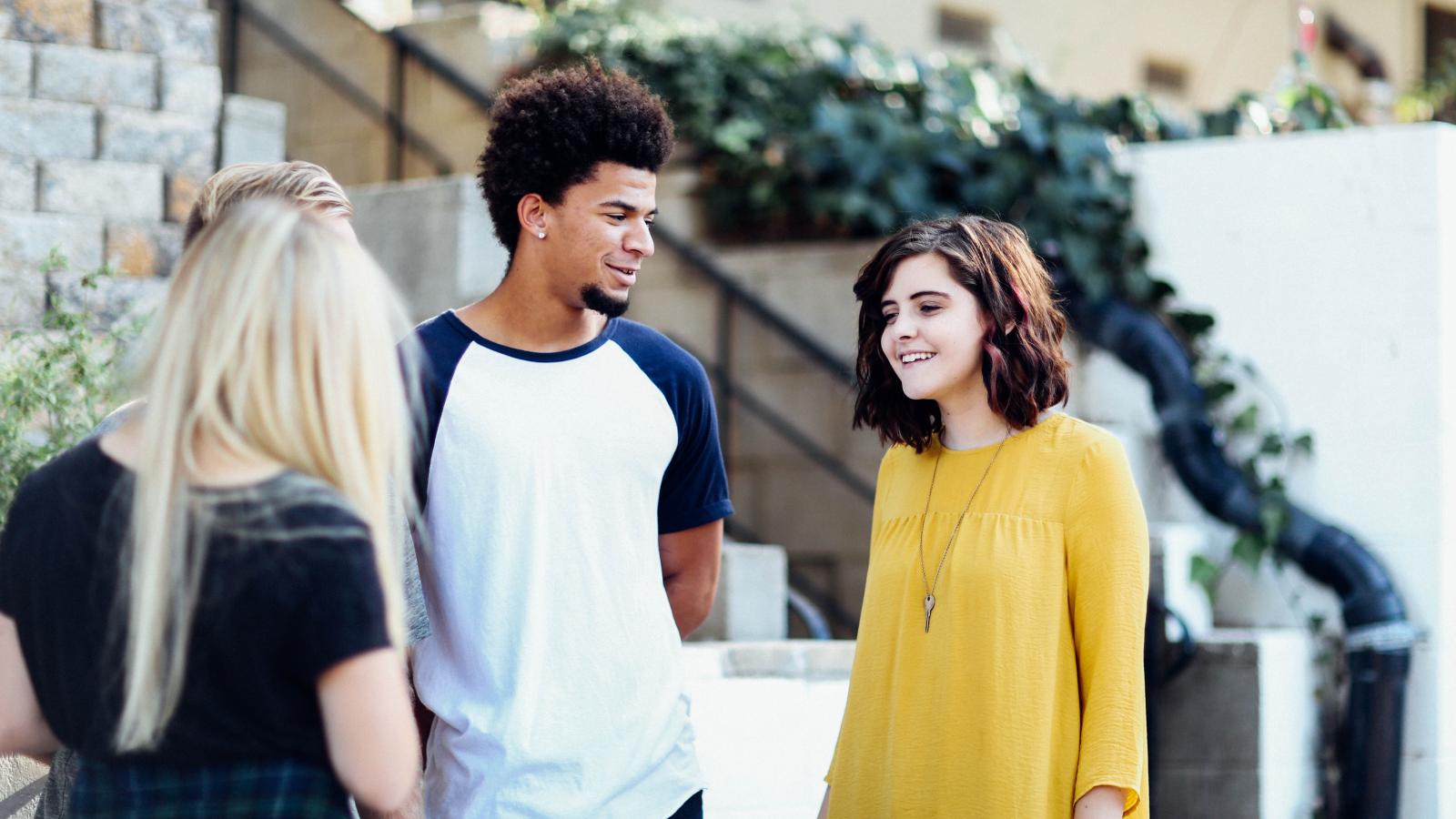 A group of teenagers stand chatting to each other