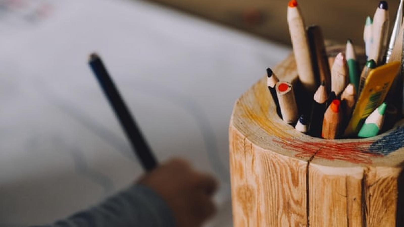 A carton of colouring pencils sits to the right of a child's hand drawing