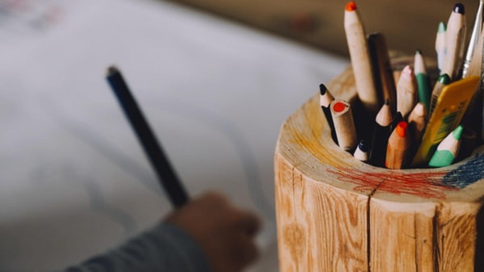 A carton of colouring pencils sits to the right of a child's hand drawing