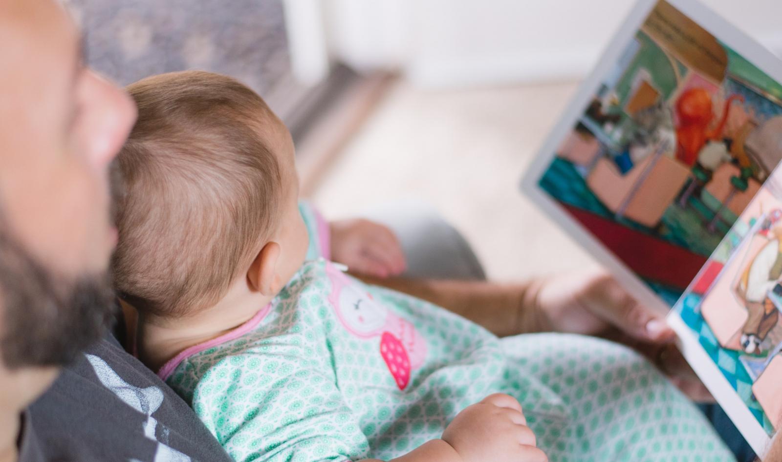 father with a young child on his lap and a book open