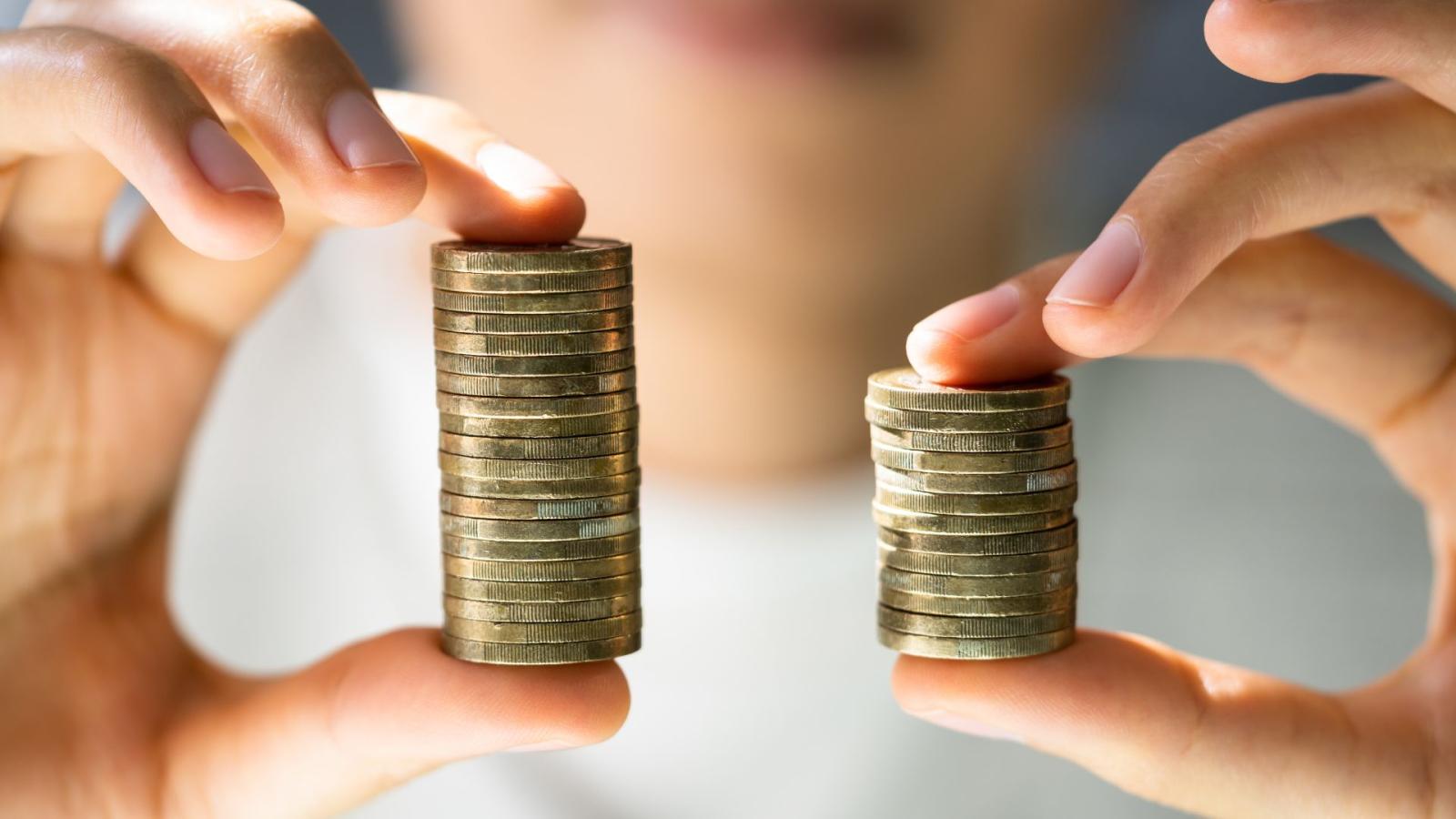 A person holding two stacks of coins, one is larger than the other