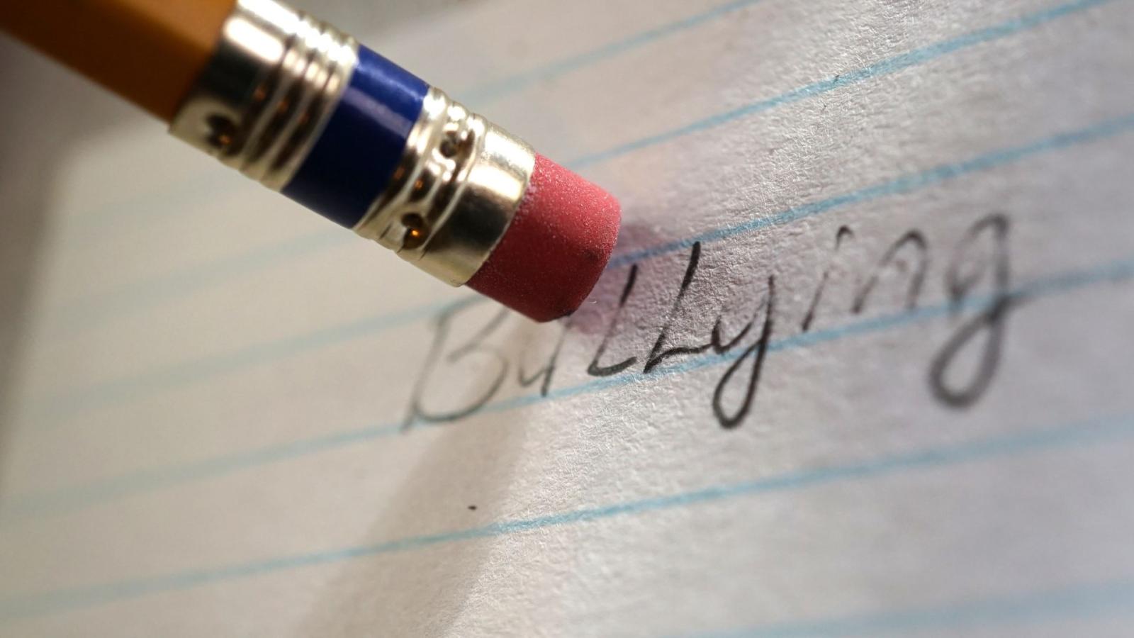 Close up of the back of a pencil with an eraser rubbing out the word "bullying"