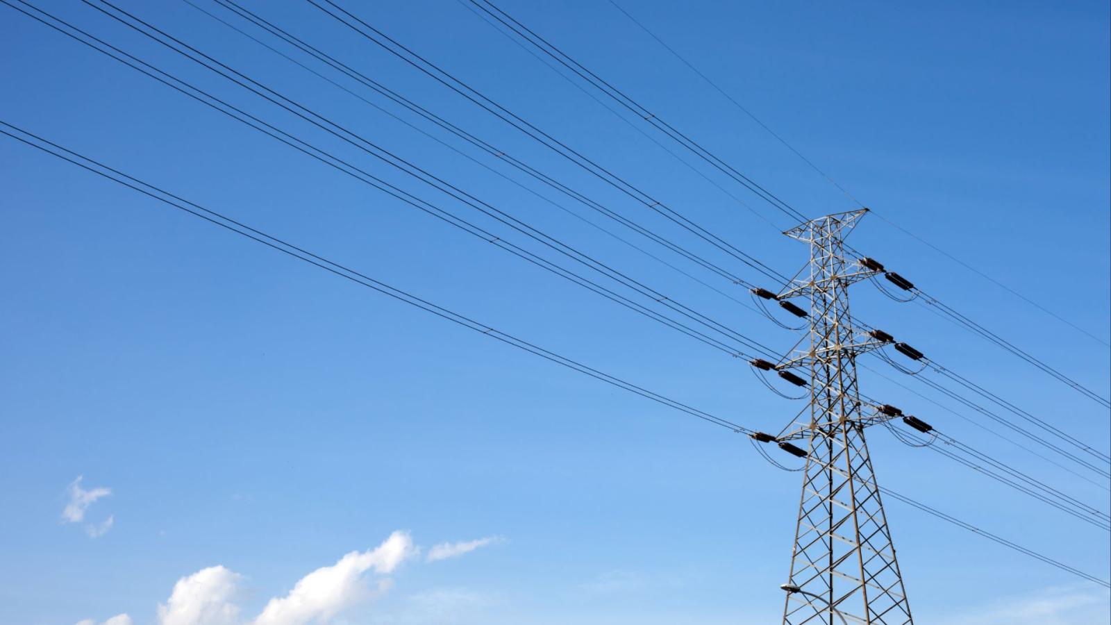Transmission tower with power lines stretching across a clear blue sky.