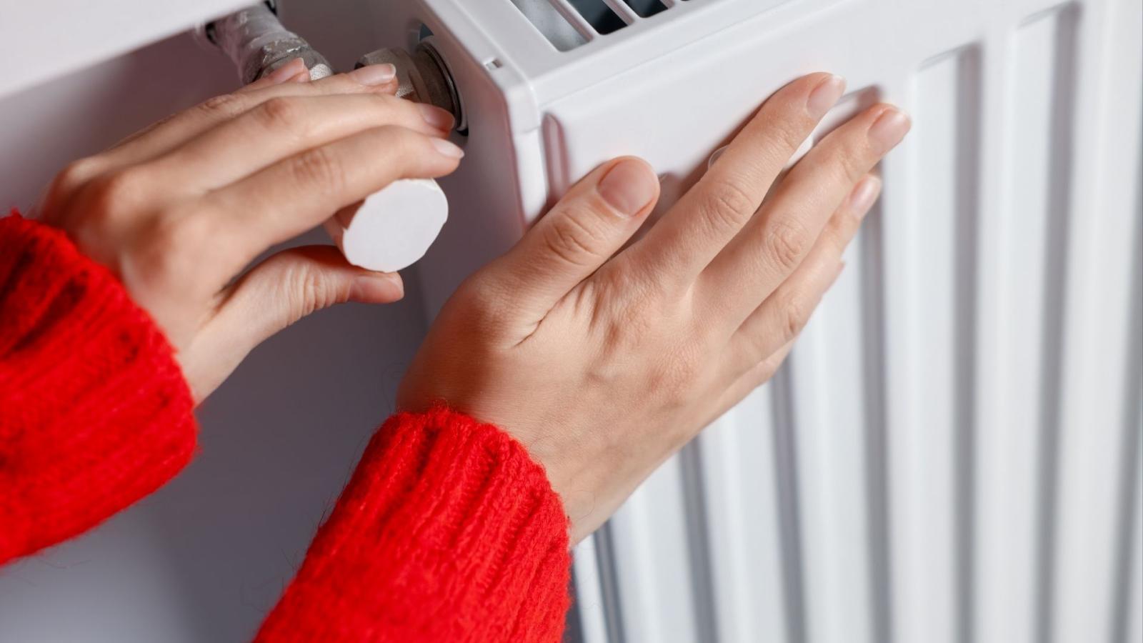 A close up of a person's hands turning on a radiator